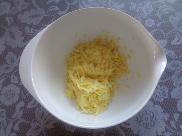 Kartoffeln waschen, schälen und in eine Schüssel raffeln