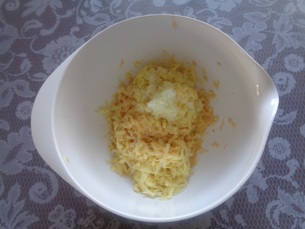 Zwiebel schälen, raffeln und zu den Kartoffeln geben