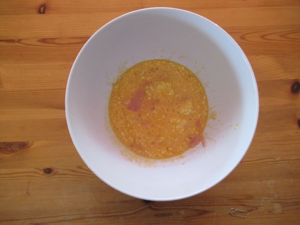 Schinken und Reibkäse zu den aufgeschlagenen Eiern geben, mit Aromat würzen